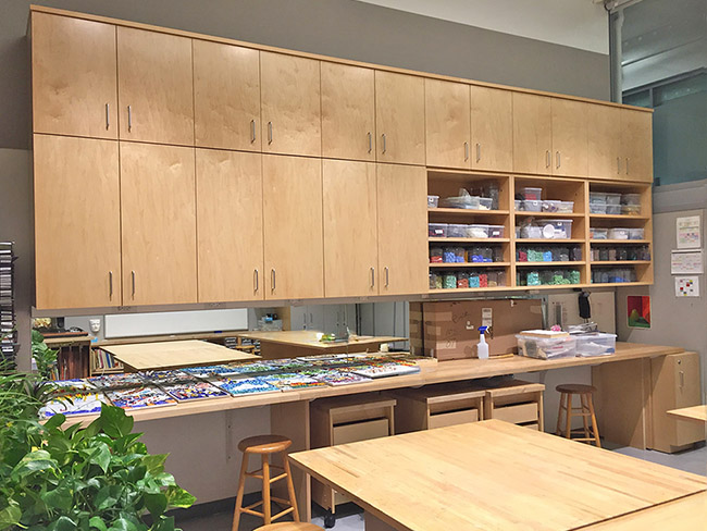 Art studio classroom furniture has hanging art storage cabinetry, adjustable art supply storage shelves, and deep art supply storage drawers. There are mobile art classroom worktables that roll on wheels and lock in place. All art table art work surfaces have solid maple butcher block tops. The artist work table counters are secured by rolling art supply storage cabinets. Art Boards art studio work tables store artist materials, art in progress and finished art. All art supplies are kept safe and clean behind art storage cabinet doors.